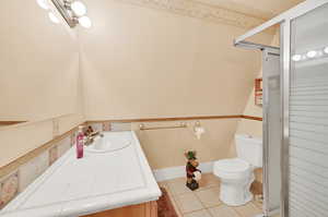 Bathroom with tile patterned floors, toilet, a shower with door, and vanity