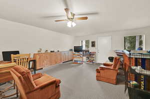 Interior space with lofted ceiling, ceiling fan, and light carpet