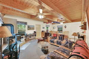 Tiled living room featuring wooden ceiling, ceiling fan, a wood stove, and beam ceiling