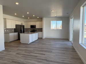 Kitchen featuring white cabinetry, stainless steel appliances, a healthy amount of sunlight, sink, and a kitchen island with sink