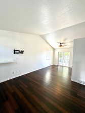 Unfurnished living room featuring dark hardwood / wood-style flooring and a textured ceiling