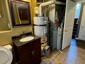 Bathroom featuring toilet, tile patterned flooring, vanity, secured water heater, and heating unit