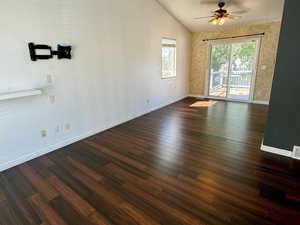 Spare room featuring dark wood-type flooring, ceiling fan, lofted ceiling, and a textured ceiling