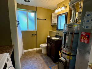 Bathroom with vanity, a healthy amount of sunlight, strapped water heater, and washer / clothes dryer