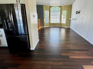 Unfurnished living room featuring dark hardwood / wood-style flooring and a textured ceiling