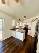 Kitchen featuring lofted ceiling, black / electric stove, kitchen peninsula, and white cabinetry