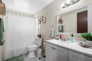 Bathroom with a shower with curtain, toilet, and vanity