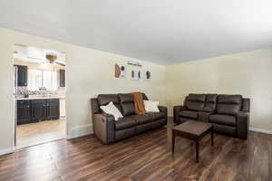 Living room with dark wood-type flooring, ceiling fan, and sink