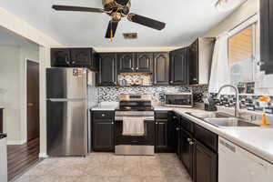 Kitchen featuring appliances with stainless steel finishes, tasteful backsplash, sink, ceiling fan, and light wood-type flooring