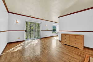 Living room with hardwood, ornamental molding, and sliding glass door to patio