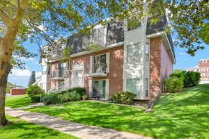 View of front of property featuring a balcony and a front yard