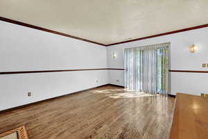 Living room with hardwood / wood-style flooring, ornamental molding, and a textured ceiling