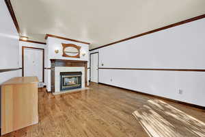 Unfurnished living room with a tiled fireplace, light hardwood / wood-style floors, and ornamental molding