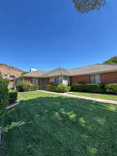 Grass area of brick home with mountain view in back.  Front faces south