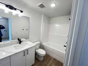 Full bathroom featuring tub / shower combination, hardwood / wood-style floors, vanity, and toilet