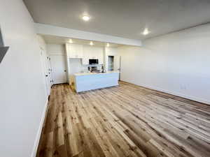 Kitchen with white cabinets, sink, light hardwood / wood-style floors, appliances with stainless steel finishes, and a textured ceiling