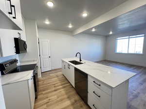 Kitchen featuring an island with sink, sink, stainless steel dishwasher, range, and light hardwood / wood-style floors