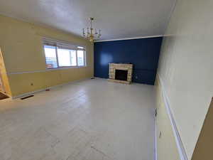 Unfurnished living room with a fireplace, an inviting chandelier, and a textured ceiling