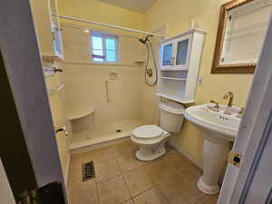 Bathroom with a shower, toilet, and tile patterned floors