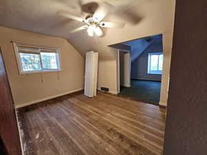 Bonus room with lofted ceiling, ceiling fan, wood-type flooring, and a textured ceiling