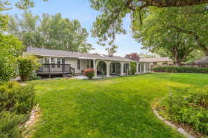 Back of property featuring a patio, a lawn, and a wooden deck