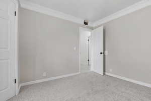 Carpeted spare room featuring ornamental molding