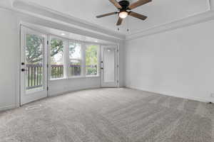 Unfurnished room with light colored carpet, ceiling fan, and a raised ceiling