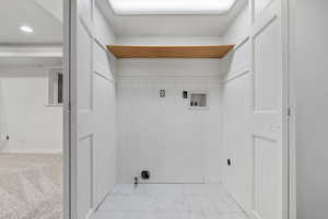 Laundry area with light colored carpet, washer hookup, and wooden walls