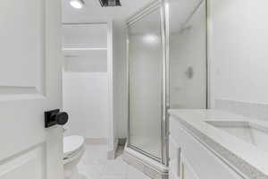 Bathroom with toilet, an enclosed shower, and vanity