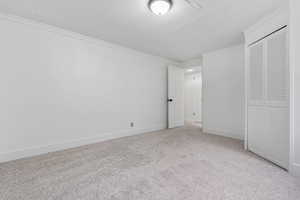 Unfurnished bedroom with a closet, light colored carpet, and ornamental molding