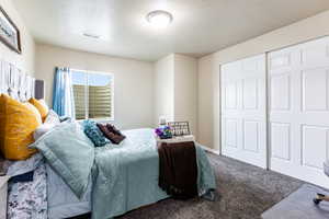 Bedroom featuring a closet, a textured ceiling, and carpet