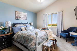 Bedroom featuring ceiling fan, carpet, and vaulted ceiling