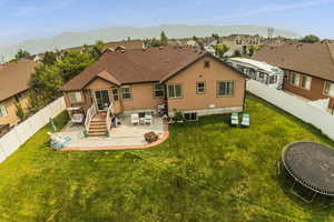 Back of house with a mountain view, a patio, a trampoline, a yard, and central AC unit