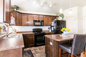 Kitchen with sink, black appliances, a kitchen breakfast bar, a kitchen island, and decorative backsplash