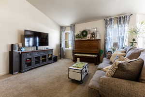 Living room with vaulted ceiling, a textured ceiling, and carpet