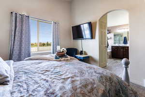 Bedroom with light hardwood / wood-style flooring and connected bathroom