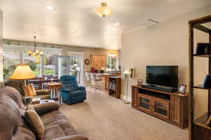 Carpeted living room with a textured ceiling and an inviting chandelier