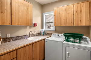 Laundry room with washer and dryer, cabinets, and sink