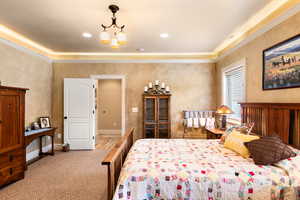 Carpeted bedroom with crown molding and a notable chandelier