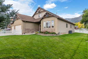 View of front of home with a mountain view, central air condition unit, and a front yard