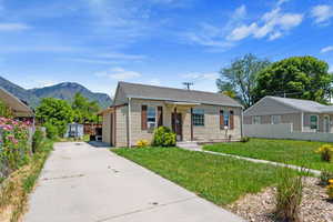 Bungalow featuring a storage shed, a mountain view, and a front yard