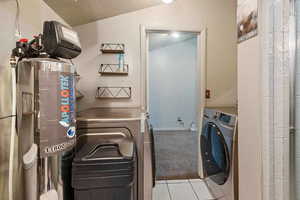 Clothes washing area featuring washer / clothes dryer and light colored carpet