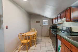 Kitchen featuring light tile patterned floors, a textured ceiling, vaulted ceiling, and black appliances