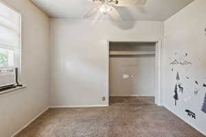 Unfurnished bedroom with a textured ceiling, carpet flooring, ceiling fan, and a closet