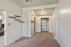 Hall with light colored carpet, a textured ceiling, and vaulted ceiling