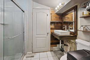 Bathroom featuring tile patterned flooring, vaulted ceiling, an enclosed shower, and toilet