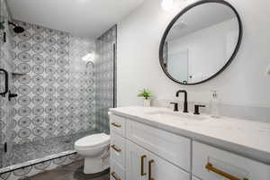 Bathroom featuring tiled shower, toilet, and vanity