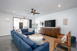 Living room with ceiling fan and concrete flooring