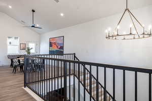 Corridor featuring hardwood / wood-style floors, high vaulted ceiling, and an inviting chandelier