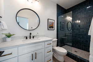 Bathroom featuring vanity, toilet, hardwood / wood-style floors, and a tile shower